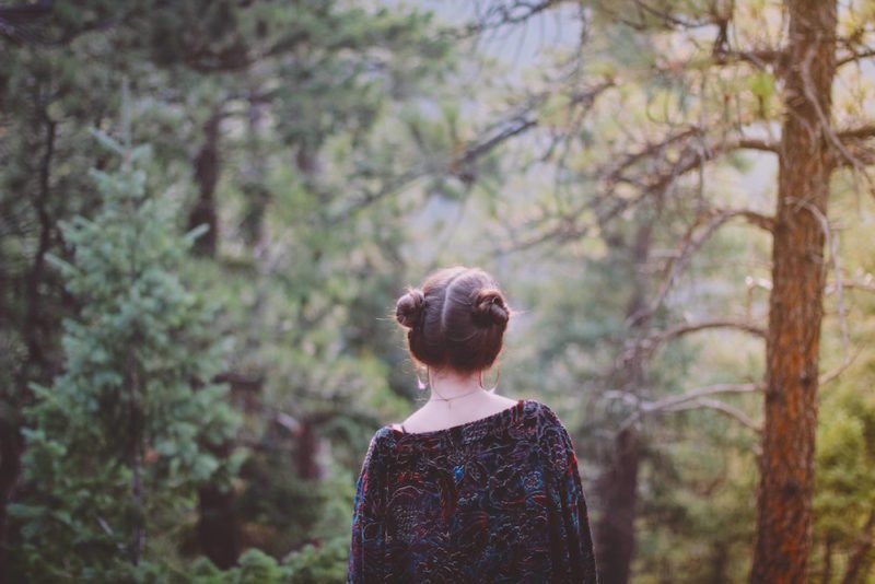 life after dieting: a photo of a woman with her hair up in two side buns, her back to the camera, standing in a forest