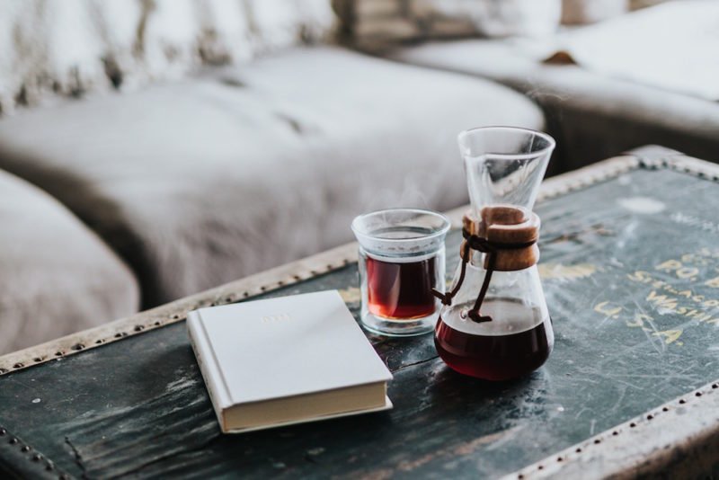 life after dieting: photo of a steamer trunk as a coffee table in front of a comfortable couch. On the steamer truck are a Chemex coffee maker, a glass mug of coffee, and a hard-bound book.