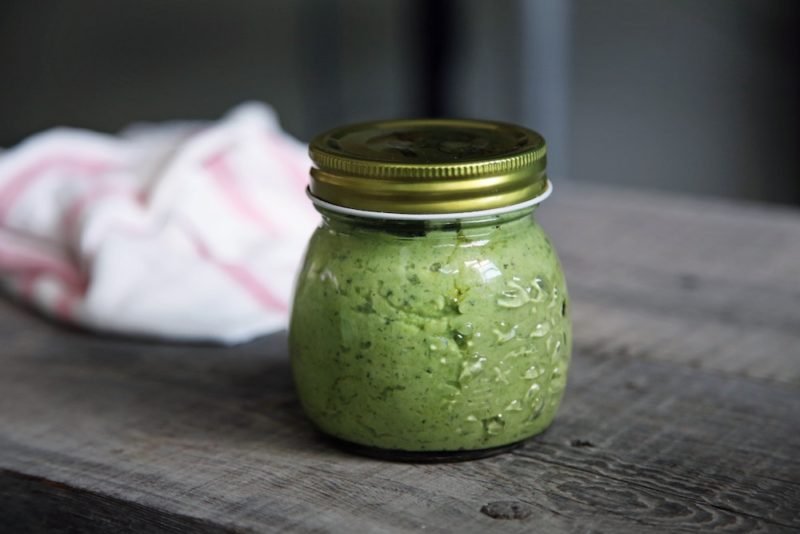 Basil Pesto: Photo of a canning jar of pesto on a rustic wood tabletop