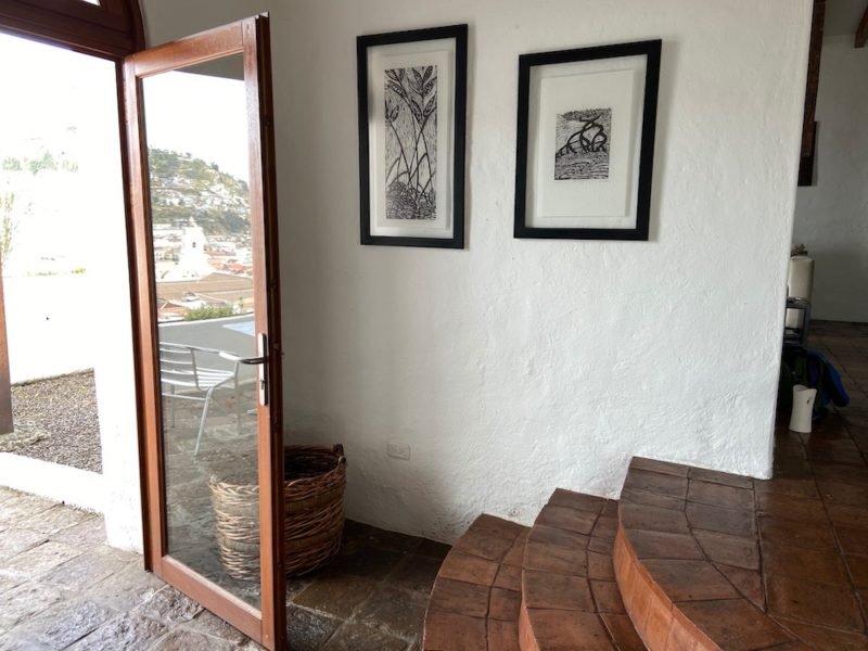 Minimalism: Photo of an apartment entryway, with terra cotta and stone tiles, and open door to a tiled patio, and rustic white walls with two black-framed black-and-white drawings.