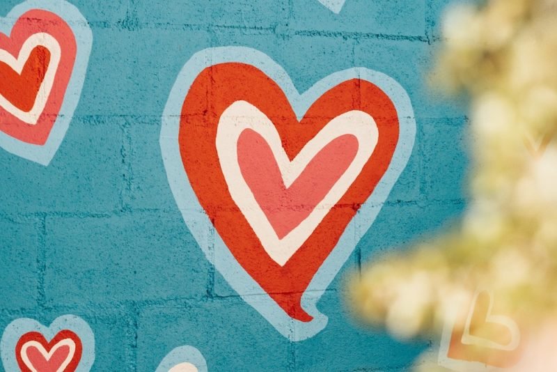 New Year's resolutions are prone to failure. Try setting New Year's intentions instead. Photo of red, white and pale blue hearts painted on a brick wall that's been painted turquoise.