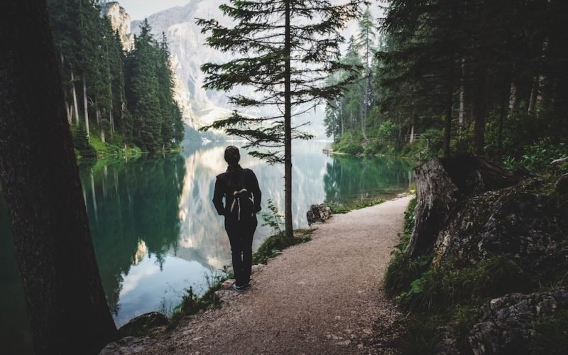 When you set New Year's intentions instead of resolutions, you give yourself a wider path, as in this photo of a young woman standing on a wooded nature trail next to a lake, that allows you to navigate around obstacles and makes it harder to make "one false step."