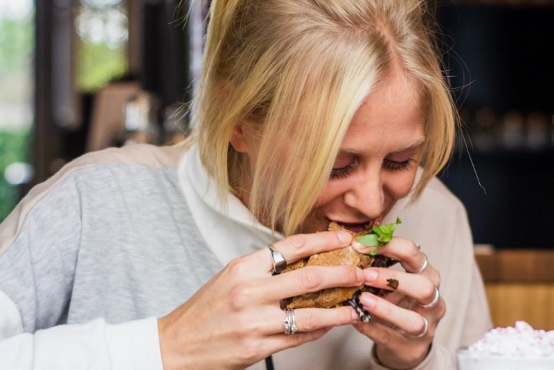 woman eating a hamburger, enjoying food freedom