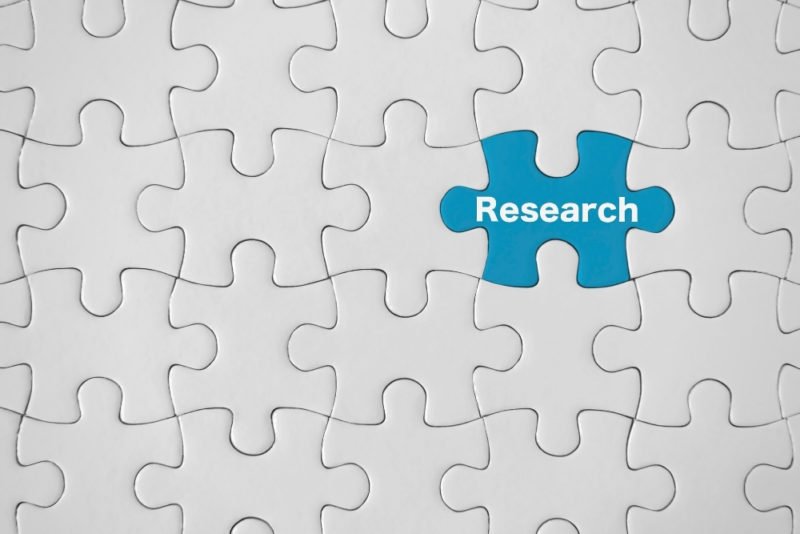 Image of white jigsaw puzzle with one blue piece that says "research."