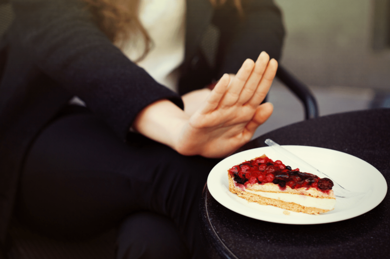 Close-up of woman's hand in a "no" or "stop" position in front of a plate of cranberry tart.