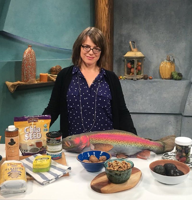 Photo of Carrie Dennett, a registered dietitian nutritionist in Seattle WA standing behind a counter in a TV studio