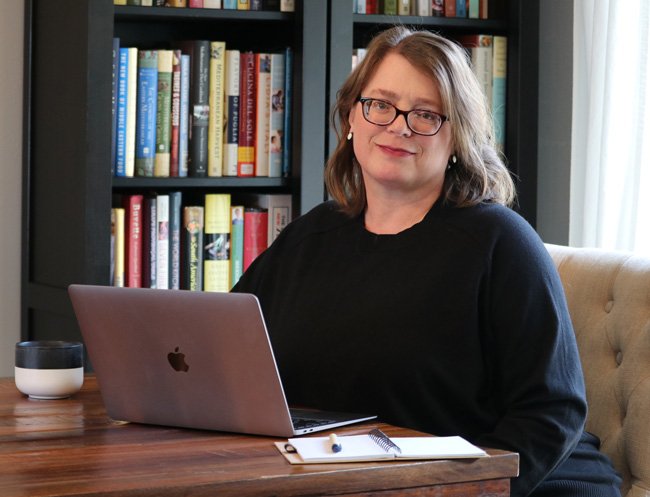 Photo of Carrie Dennett, a registered dietitian nutritionist in Seattle WA sitting at her laptop in front of a bookcase.