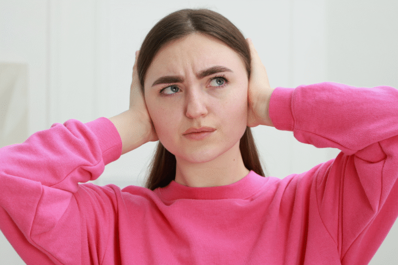 Photo of young woman covering her ears because she doesn't want to hear what someone's saying. Setting diet talk boundaries is important if you want to avoid listing to talk about weight loss.