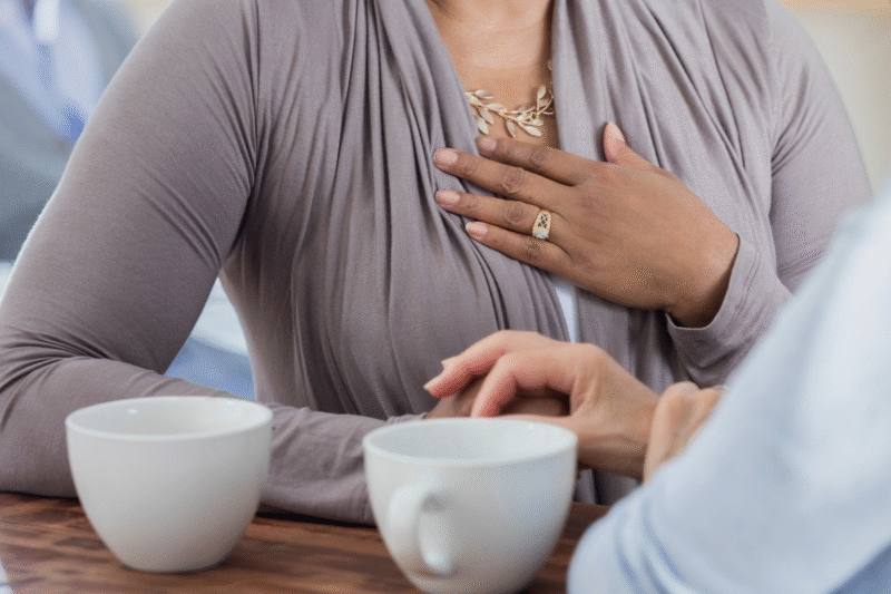 Photo of two women talking over coffee, one with her hand on her heart. When setting diet talk boundaries, sometimes it helps to talk to the person privately rather than brining it up in a group setting.