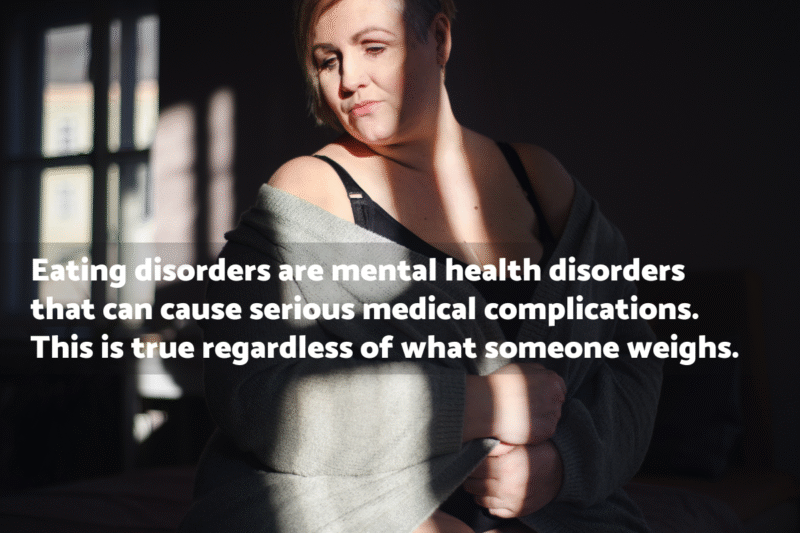 Photo of a middle-aged woman wearing a black bra with a blanket wrapped around her in a shadowy room. The text overlay says "Eating disorders are mental health disorders that can cause serious medical complications. This is true regardless of what someone weights."